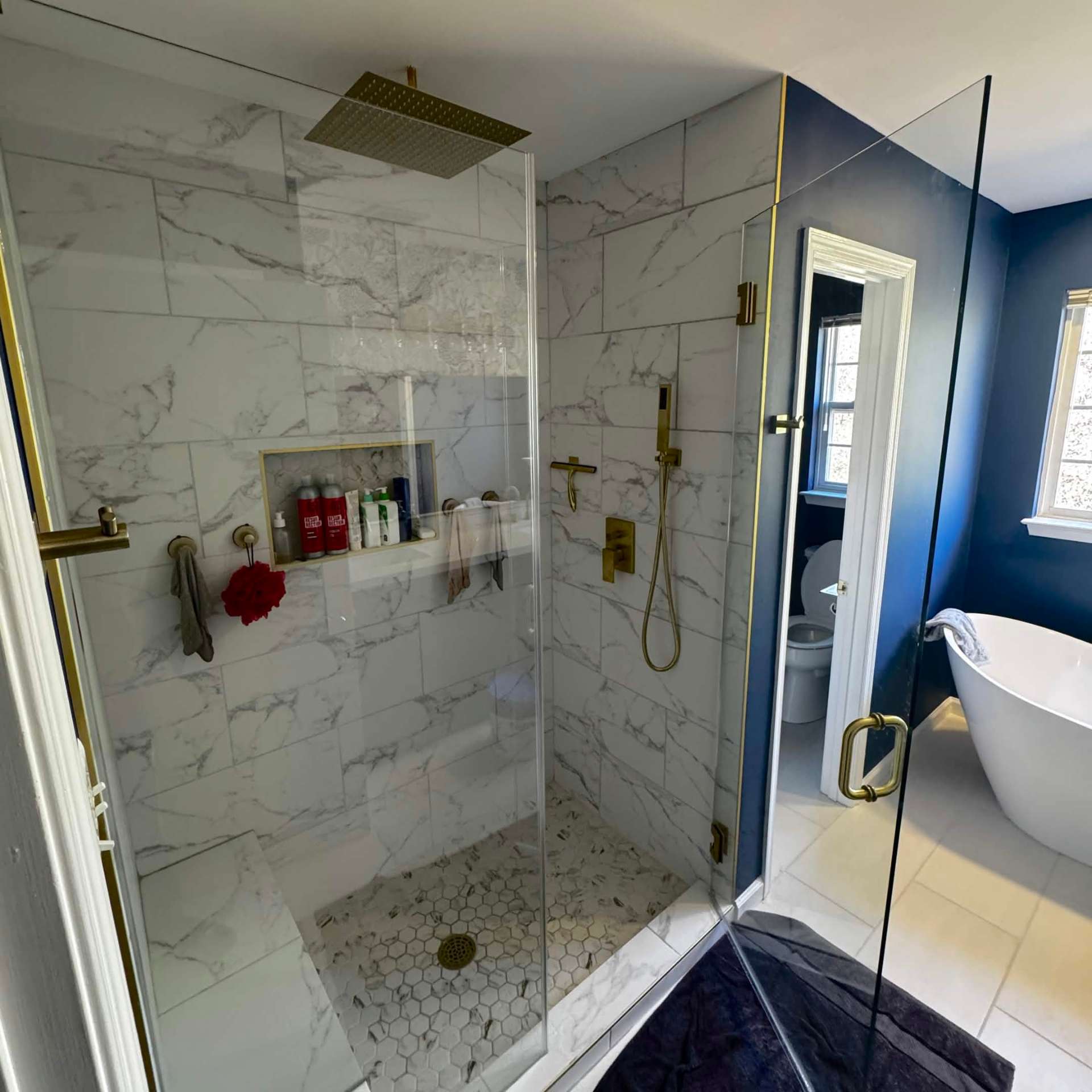 Marble corner shower with brushed gold fixtures