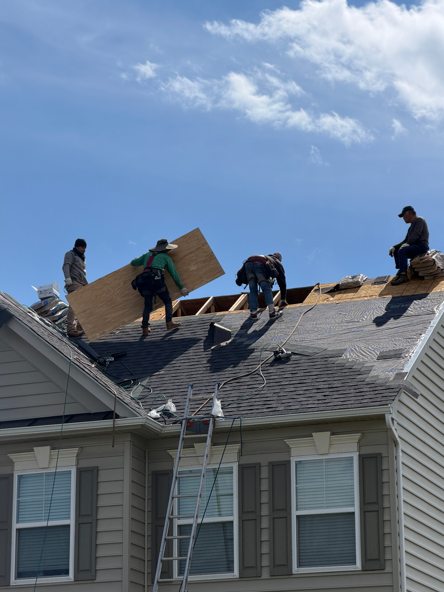 Perpetual Improvements roofing crew installing new plywood roof decking and architectural asphalt shingles during a full residential roof replacement.