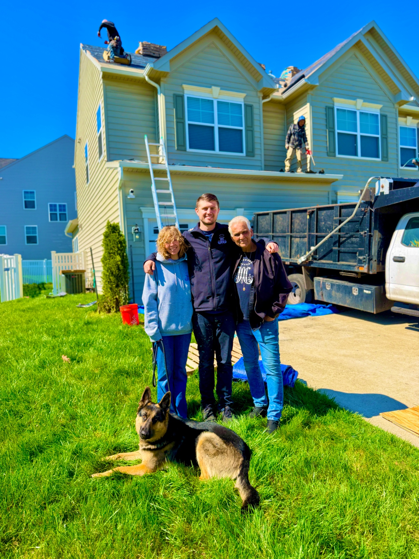 Perpetual Improvements roofing crew posing in front of a residential home and dump truck after completing a full asphalt shingle roof replacement.